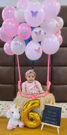 a baby is sitting in a basket with balloons