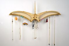 a wooden bat hanging on the wall with many necklaces and rings attached to it