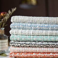 a stack of towels sitting on top of a table next to a vase with flowers