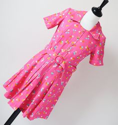 SUPER CUTE! Perfectly formed 1970's summer mini-dress in bright bubblegum pink cotton patterned with daisies and blue cherries. The cotton is a dense high quality and the colours are crisp. Details include the semi-pleated skirt, decorative button trim and matching buckle belt. The old vintage size label says '38' but in my opinion the fit is much smaller and like an XXS / XS or a UK 6 / 8 We advise that you check all the measurements below. The garment is mid-weight and is lined. Excellent Cond Pink Retro Print Summer Dress, Pink Casual Dress With Retro Print, Casual Pink Dress With Retro Print, Fitted Pink Cotton Dress, Playful Fitted Spring Dresses, Fitted Cotton Dress With Retro Print, Playful Fitted Dresses For Spring, Cotton Dresses With Retro Print For Summer, Cotton Short Sleeve Dresses With Retro Print