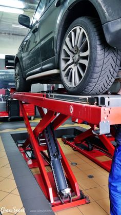 a car on a lift being worked on by a service worker in a garage or repair shop