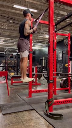 a man standing on top of a red rack in a gym