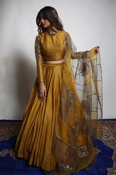 Burnt gold and grey dupion silk lehenga with heavily embroidered sleeves. Comes with a padded blouse and an organza dupatta having dual coloured patchwork, including zari and sequins hand embroidered chakra motifs .
Component: 3
Pattern: Embroidered
Type Of Work: Zari, Sequins
Neckline: V Neck
Sleeve Type: Three quarter
Fabric: Lehenga and Blouse: Dupion Silk, Dupatta : Organza 
Color: Gold
Other Details: 
Closure : Blouse : Back with Hook and Eye, Lehenga : Opening on the side with Zip and Hook Long Sleeve Lehenga, Lehenga With Long Choli, Organza Lengha, Hand Work Lehenga, Zari Lehenga, डिजाइनर कपड़े, Long Blouse Designs, Gold Lehenga, Simple Lehenga