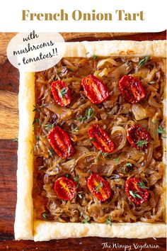 a square pastry with onions and tomatoes in it on top of a wooden table next to a sign that says french onion tart