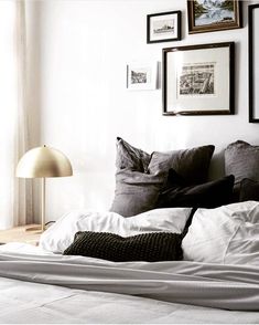 a bed with white sheets, pillows and pictures on the wall