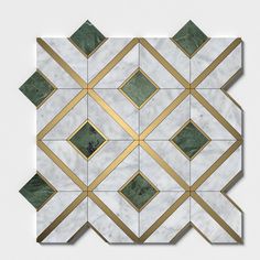 a white marble and gold geometric tile with diamond shapes on the top, along with green accents