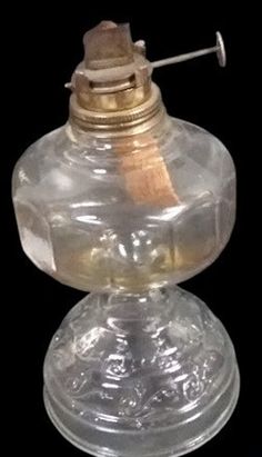 an old fashioned oil lamp with a wooden stick sticking out of it's top