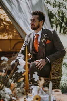 a man sitting in a chair with an orange tie