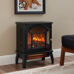 a fireplace with a fire burning in it next to a chair and painting on the wall