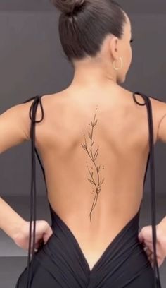 the back of a woman's body with a tattoo on her lower back and neck