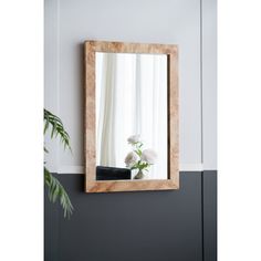 a mirror hanging on the wall above a vase with flowers