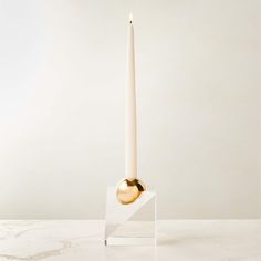 a white candle holder with a gold ball on it and a marble base in the middle