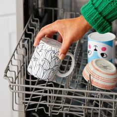 a person is holding a coffee mug in their dishwasher