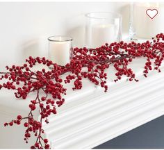 red berries and candles sit on a mantel