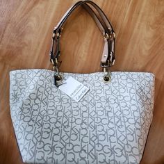 New Calvin Klein Tote Bag With Tag *Authentic* Cream/Beige/Brown/Gold Detachable Handles Reversible Inside Out Tote To Bucket Bag Magnetic Closure 18" L Top 11" L Bottom 11" H Condition Excellent New With Some Minor Scratches On Attachment Of The Handles. Never Been Used. Beige Satchel With Branded Hardware For Daily Use, Casual Shoulder Bag With Branded Hardware, Casual Bags With Branded Hardware And Double Handle, Trendy Beige Bag With Branded Hardware, Casual Bags With Double Handle And Branded Hardware, Casual Shoulder Bag With Branded Hardware For Daily Use, Casual Satchel With Branded Hardware For Daily Use, Casual Tote Shoulder Bag With Branded Hardware, Calvin Klein Top Handle Shoulder Bag