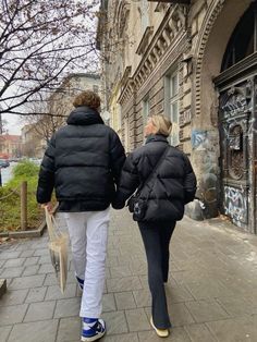 two people walking down the street holding hands