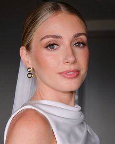 a woman wearing a white dress and gold earrings