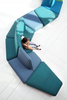 a woman laying on top of a blue couch next to a white tiled floor in a room