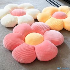 four different colored flower shaped cushions on the floor