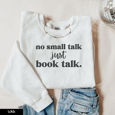 "Dive into the world of books with our \"No Small Talk, Just Book Talk\" crewneck sweatshirt, a perfect pick for every booktrovert and bookworm out there! This reading sweater is a dream come true for anyone who prefers the magic of pages to everyday chatter, making it a top choice in bookish gift ideas. Whether you're cozied up in a library sweatshirt or sharing your love for fantasy reader merch and romantasy at your next bookclub meeting, this sweatshirt speaks volumes about your passion. It's an ideal bookclub gift, and for those active on BookTok, this booktok sweatshirt will definitely resonate with your followers. Pair it with your favorite bookish thing and celebrate being a proud book bestie. Grab this bookclub sweatshirt now and let your bookish love shine! ** DETAILS ** This uni Bookish Merch Ideas, Bookish Sweatshirt With Letter Print And Crew Neck, White Bookish Sweatshirt With Letter Print, Bookish Cotton Sweatshirt With Letter Print, Cotton Letter Print Bookish Sweatshirt, Book Merch Ideas, Library Sweatshirt, Bookish Tees, Bookish Designs