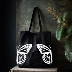 "This Butterfly Tote Bag will be your next everyday bag. Whether it's used as a grocery bag, school bag, or as a work bag; it will be the perfect bag or yourself to give as a gift.  The minimalist design will match everything but is unique enough can stand out on its own! Standard Tote Bag Classic Canvas 100% Cotton Dimensions: 15\"W x 16\"H , 21\" Handles Large Canvas Tote Bag Heavy Canvas with squared off bottom Dimensions: 20\"W x 15\"H x 5\"D , 23\" Handles Heavy Canvas Zipper Tote Bag  Heav Recyclable Travel Bag For Back To School, Everyday Tote Shoulder Bag For Back To School, Casual School Bags Recyclable, Casual Recyclable School Bag, Large Eco-friendly School Bag, Recyclable Everyday Bags For Back To School, Black Tote Bag For Back To School, Back To School Black Tote Shoulder Bag, Everyday Canvas Tote Bag For Back To School