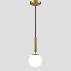 a brass colored light fixture with a white ball hanging from the ceiling, on a gray background