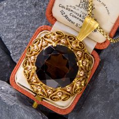 This bold pendant made in Vienna, Austria, holds an 18 carat round cut smoky quartz at its center. The frame is decorated with scrolling details and rose gold beadwork. The pendant is crafted in 14k yellow and rose gold, and the 18 inch rounded box chain it hangs from is also 14k yellow gold. Luxury Evening Jewelry With Intricate Design, Luxury Intricate Design Jewelry For Evening, Luxury Collectible Bronze Jewelry, Luxury Jewelry With Intricate Design And Round Pendant, Luxury Medallion Jewelry With Filigree, Luxury Round Pendant Jewelry With Intricate Design, Rose Gold Vintage Jewelry For Evening, Luxury Filigree Medallion Jewelry, Vintage Rose Gold Jewelry For Evening