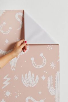 a person is holding onto a pink and white wallpaper with cactus designs on it