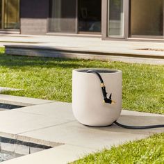 a large white vase sitting on top of a grass covered field next to a pool