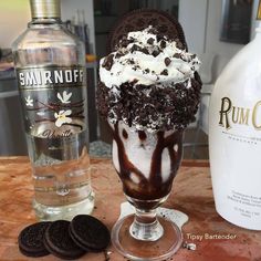 an ice cream sundae with oreo cookies and rum on the table next to it