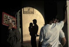 two men standing next to each other in front of a building with a sign on it