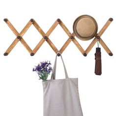 a tote bag and hat hanging on a coat rack with wooden pegs as hooks