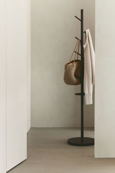 a coat rack with a basket on it next to a white wall and door in the background