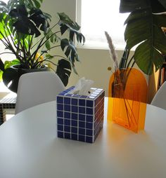 two vases sitting on top of a white table next to a potted plant