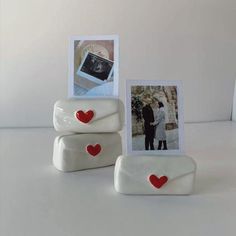 two white frames with red hearts are sitting next to each other on a table,