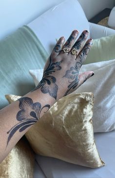 a woman's arm with tattoos on it and her hand resting on the pillow