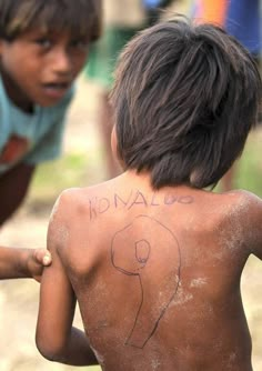 two young boys with their backs covered in mud and writing on the back of their shirts