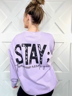 a woman with her back to the camera, wearing a purple sweatshirt that says stay