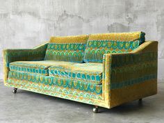 a green and yellow couch sitting on top of a cement floor