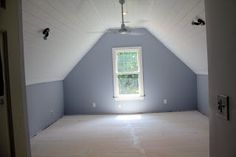 an empty room with white walls and a window in the ceiling is seen from another room