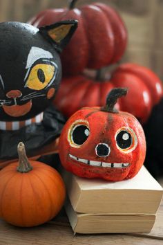 two pumpkins with faces painted on them are sitting next to each other in front of some books