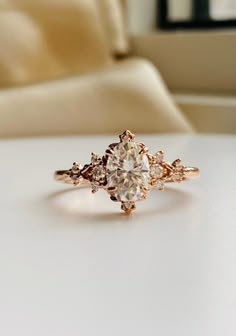 a diamond ring sitting on top of a white table next to a couch and window