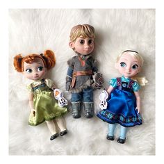 three dolls are posed on a white fur surface