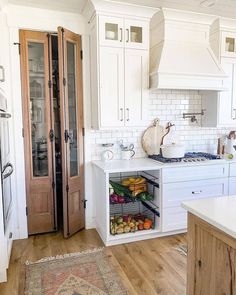 a kitchen with white cabinets and wooden floors, an area rug is on the floor