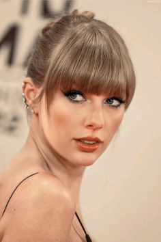 a woman with blue eyes and bangs in a black dress is posing for the camera