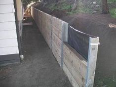 a wooden fence with a black tarp over it and some dirt on the ground