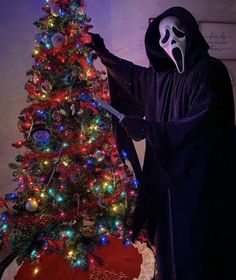 a person in a ghost costume standing next to a christmas tree