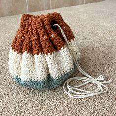 a crocheted purse sitting on top of a carpeted floor next to a wall