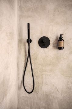 a bathroom with a black shower head and soap dispenser on the wall