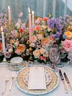 the table is set with plates, silverware, and floral centerpieces on it